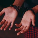 A close-up image showing hands in handcuffs, symbolizing justice and law enforcement.