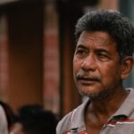 Candid portrait of a thoughtful senior man with facial hair wearing a polo shirt in Guwahati, India.