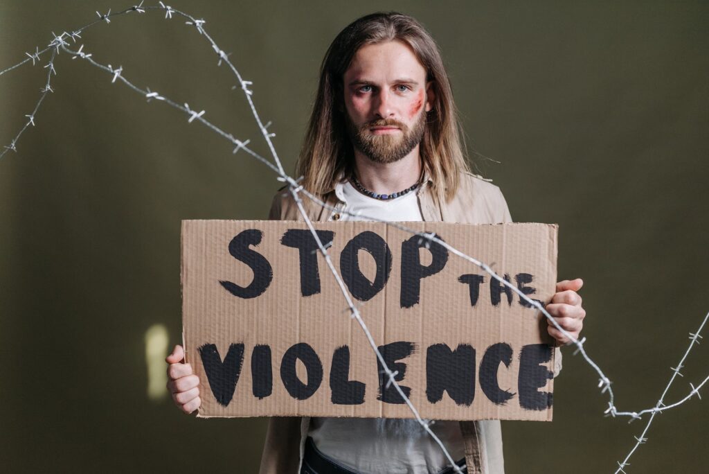 Man holding a 'Stop the Violence' sign with barbed wire emphasizing peace and protest.