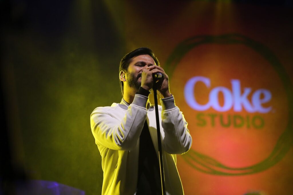 Vocalist passionately singing on stage at a vibrant Coke Studio music concert.