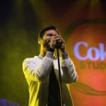 Vocalist passionately singing on stage at a vibrant Coke Studio music concert.
