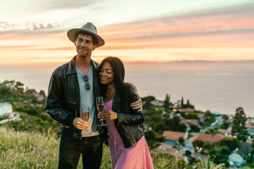 Couple enjoying champagne with a scenic ocean view at sunset.