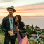 Couple enjoying champagne with a scenic ocean view at sunset.