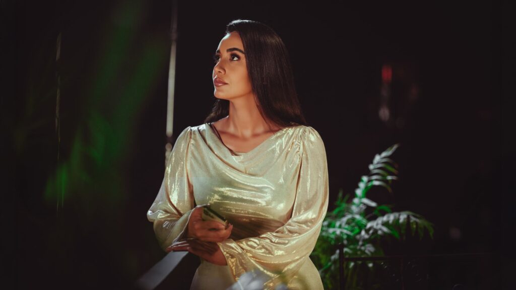 Woman in a shimmery gold dress under evening lights in Baghdad, Iraq.