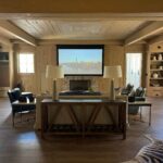Stylish living room with projector screen, cozy seating, and wooden décor.