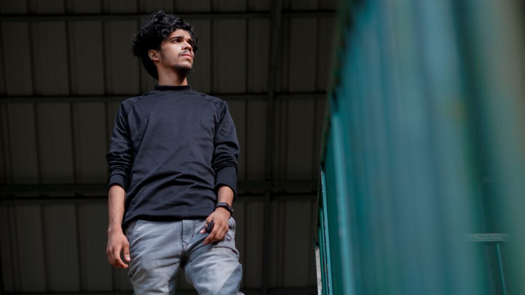 Portrait of a young South Asian man in black sweater with a confident expression.