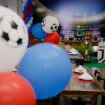 Colorful football party setup indoors with balloons and table settings, perfect for sports enthusiasts.
