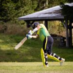 Cricketer hitting the ball during an exciting match outdoors.