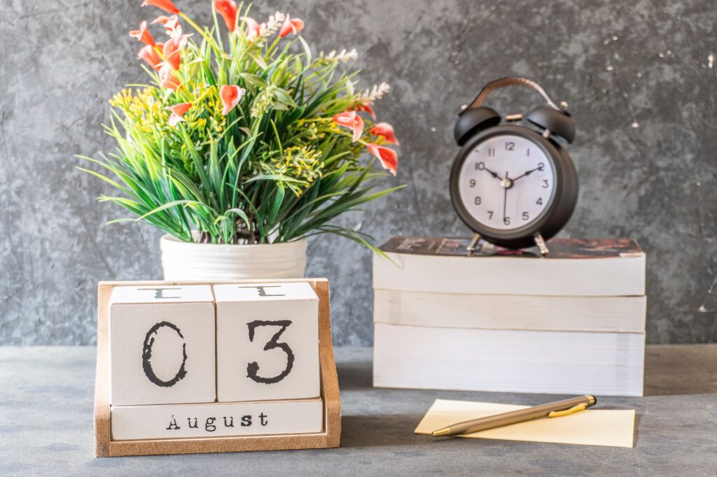 Stylish August 3rd setup with a vintage clock, flower arrangement, and calendar blocks on a desk.