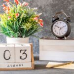 Stylish August 3rd setup with a vintage clock, flower arrangement, and calendar blocks on a desk.