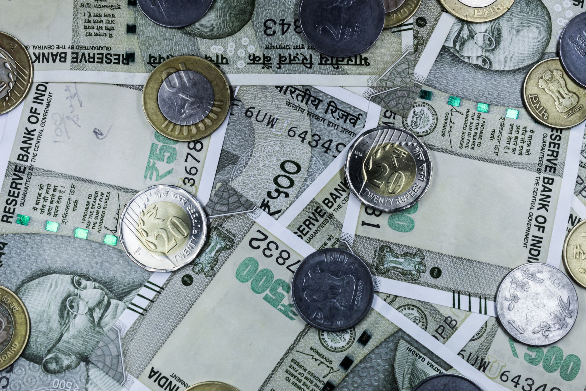 Top view of various Indian rupee banknotes and coins, highlighting financial themes.