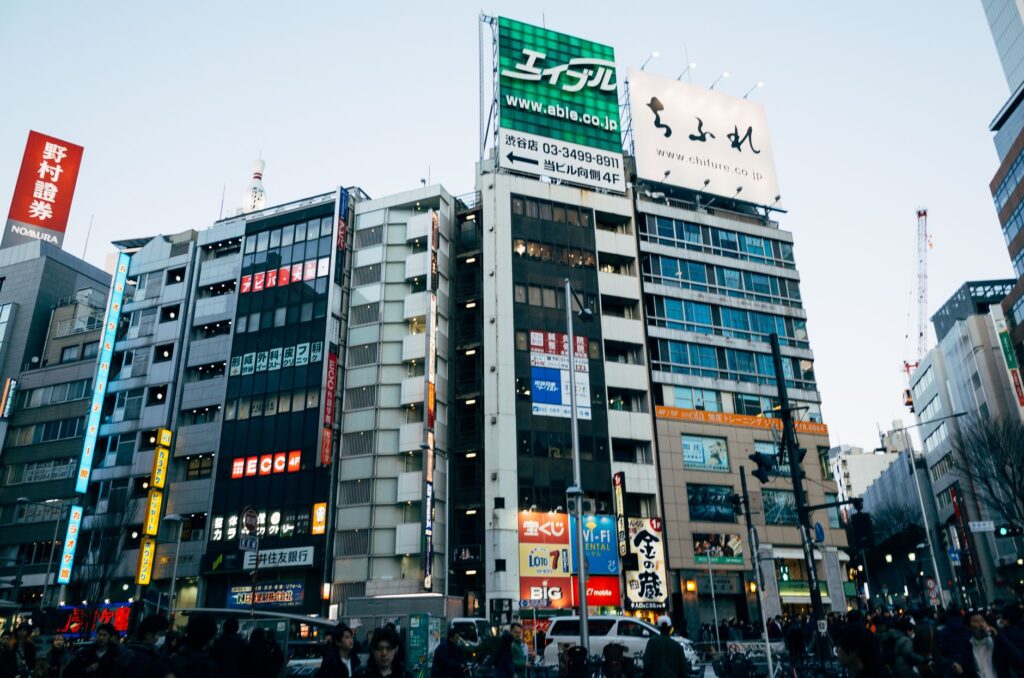 Dynamic view of a bustling Tokyo street with colorful billboards and busy pedestrian traffic.