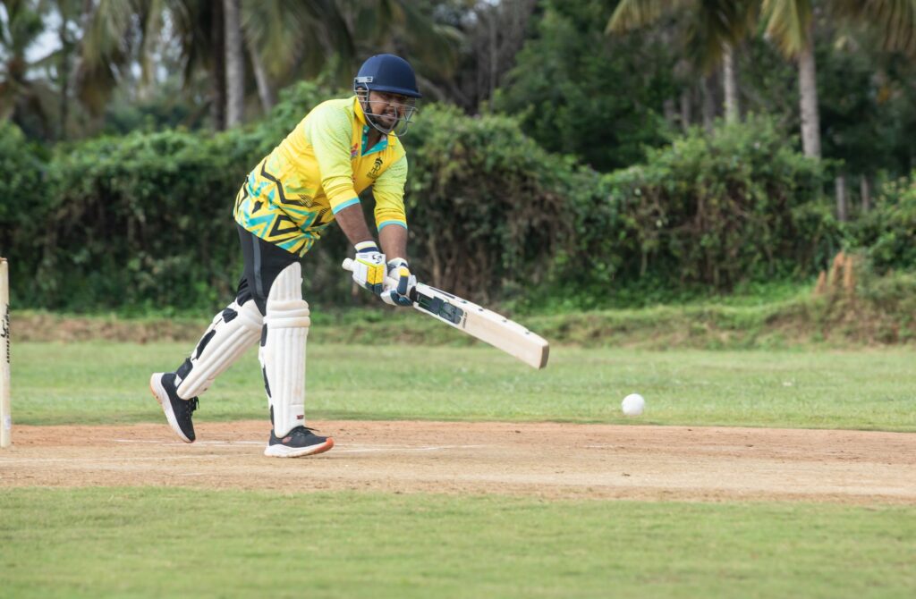 A cricket player skillfully batting on a lush outdoor field, capturing the essence of the game.