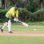 A cricket player skillfully batting on a lush outdoor field, capturing the essence of the game.
