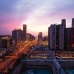 A breathtaking panoramic view of Beijing's urban skyline at dusk with vibrant city lights and a colorful sky.