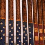 Close-up of a rusty iron fence painted with stars and stripes at the American-Mexican border in Tijuana.
