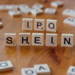 Creative representation of Shein's IPO using letter tiles on a wooden surface.