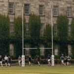 Rugby players practice on lush grounds of Trinity College Dublin.