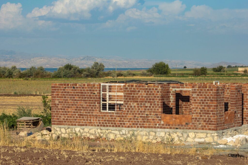 Red brick building under construction in Erzurum's rural landscape.