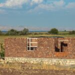 Red brick building under construction in Erzurum's rural landscape.
