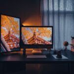 Cozy home office setup with dual monitors displaying autumn scenery.