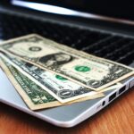 Close-up of US dollar bills placed on a laptop symbolizing digital finance and economy.