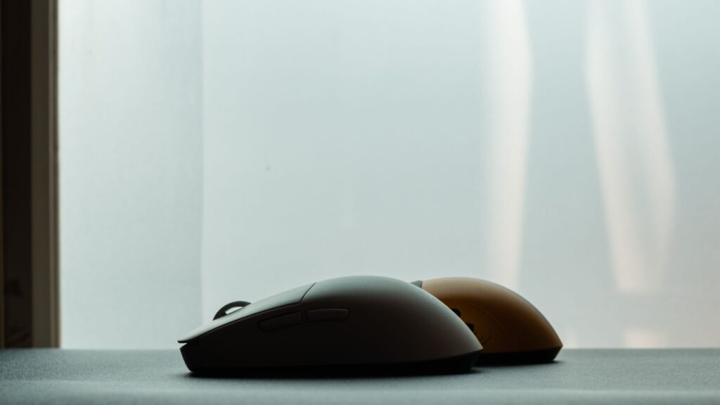 Silhouette of two wireless computer mice against a soft background, highlighting modern technology design.