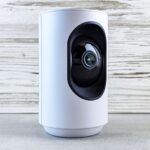 Close-up of a white indoor security camera against a wooden backdrop, showcasing modern design.