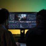 Team of two professionals video editing in a modern setup with dual monitors.