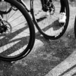 Black and white image of multiple bicycle wheels casting shadows on the ground.