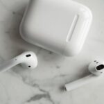 High-quality image of wireless earbuds and charging case on marble surface, showcasing modern technology.