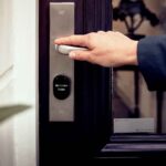 A hand opening a smart home door with digital access panel, conveying security and technology.