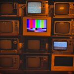 A collection of vintage televisions featuring static and color test patterns on the screens.