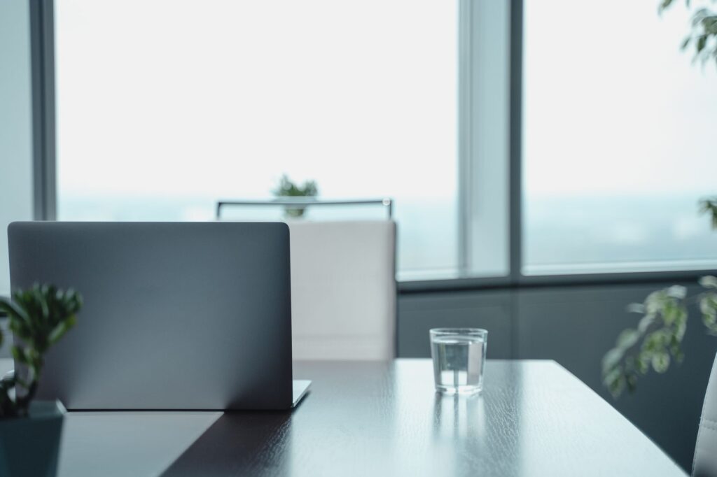 Minimalist office desk featuring a laptop and water glass in a modern business setting.