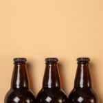 Minimalist still life of three brown beer bottles on a beige background.