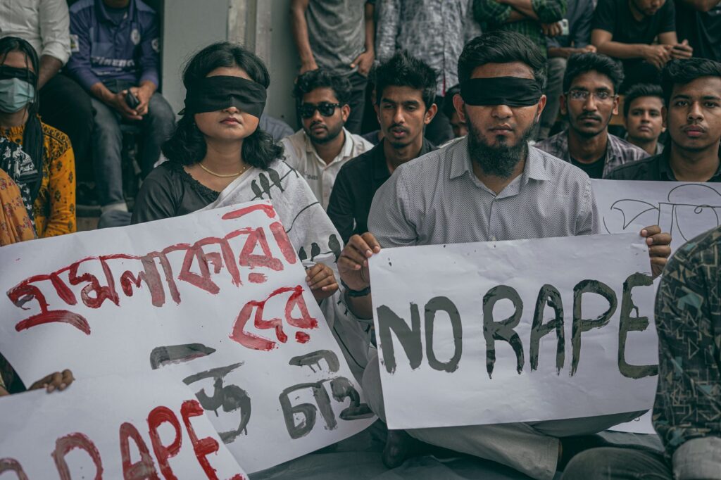A group of people protesting against sexual violence by holding signs and wearing blindfolds.