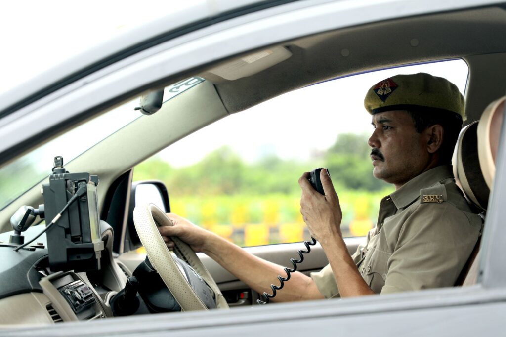 A police officer communicates via CB radio while driving a patrol vehicle, focused and on duty.