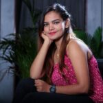 Young woman in a fashionable pose, smiling indoors with lush plants in Chennai.