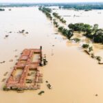 Aerial photo capturing a flooded landscape featuring a submerged brick kiln and surrounding greenery.