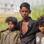 Three South Asian boys pose together in a rural setting, showcasing friendship in India.
