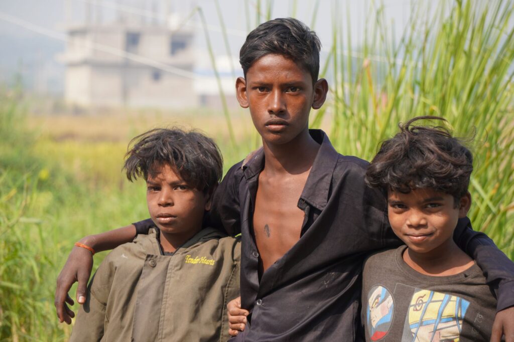 Three South Asian boys pose together in a rural setting, showcasing friendship in India.