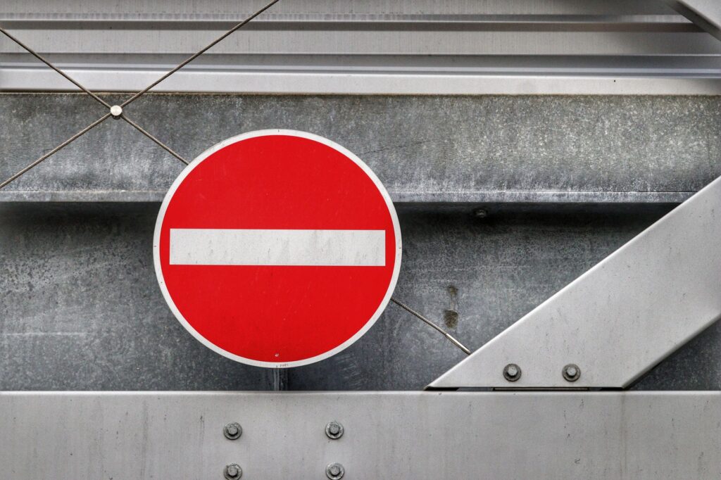 Red no entry traffic sign positioned on a metallic industrial backdrop, depicting restriction.