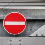 Red no entry traffic sign positioned on a metallic industrial backdrop, depicting restriction.