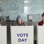 Three women voting in office cubicles. Diverse representation, focused and serious.