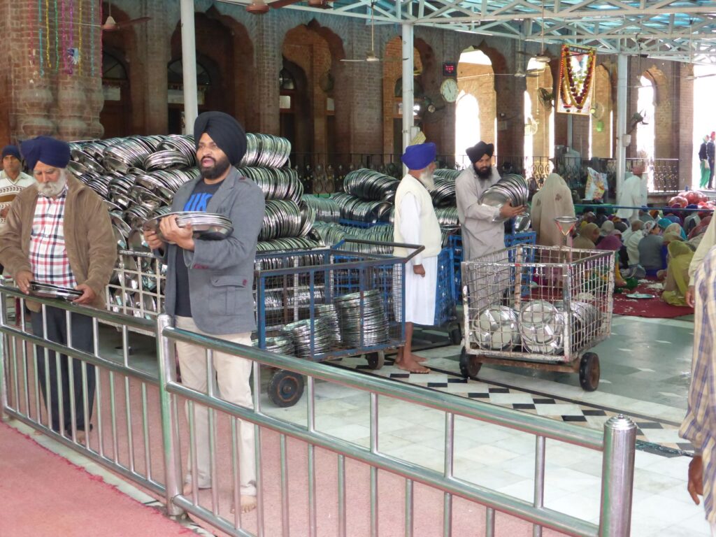Volunteers preparing plates for a community meal at a Sikh temple.