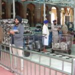 Volunteers preparing plates for a community meal at a Sikh temple.