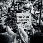 Crowd of young adults protesting with impactful signs in black and white.