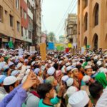 Large group of people protesting on a street with placards, showcasing civic activism.