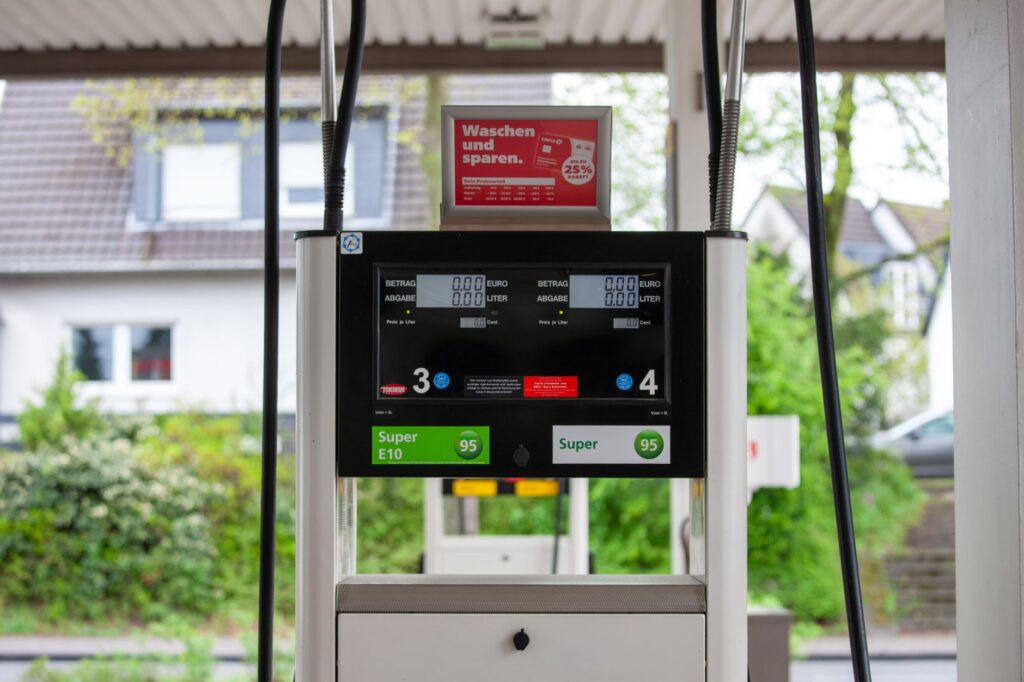 Close-up of a gas pump at a station in Bergisch Gladbach, Germany, with surrounding houses visible.