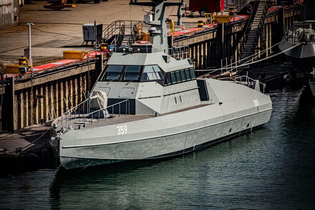 A grey military ship docked in Cherbourg-en-Cotentin, Normandy, reflecting modern naval architecture.